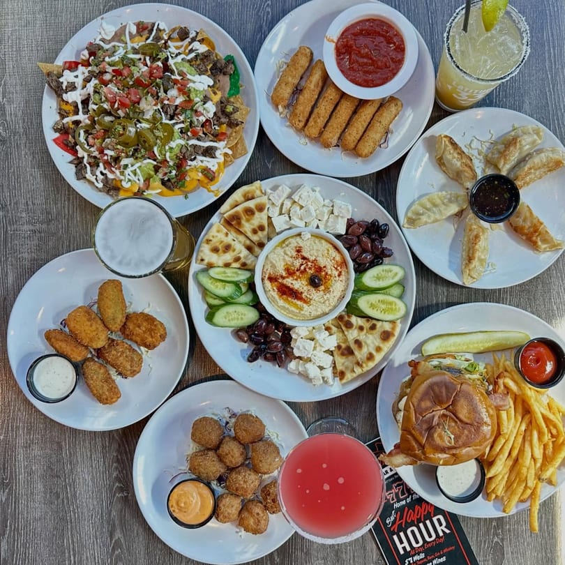 An overhead shot of a table filled with various appetizers, drinks, and a burger with fries.